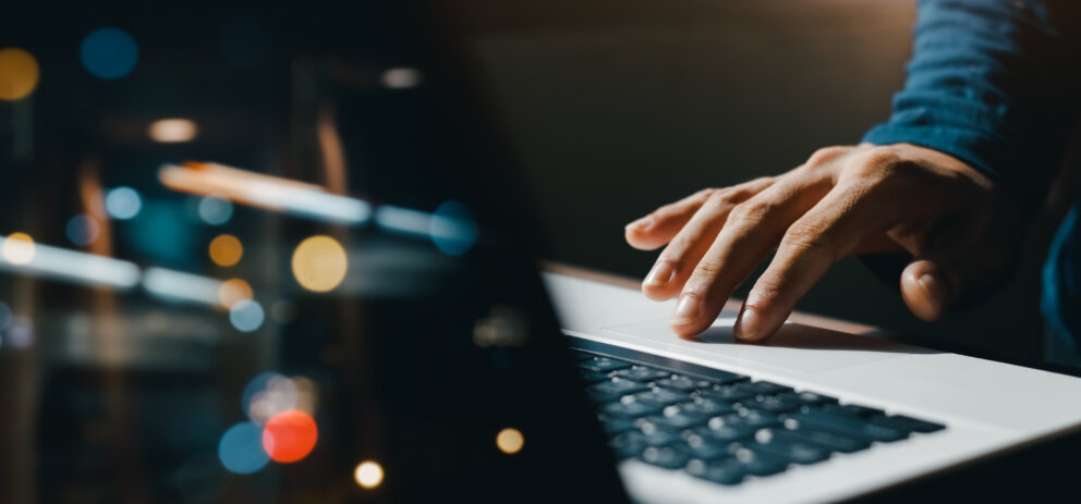 young man hand working on a laptop, bokeh blurred at night For t